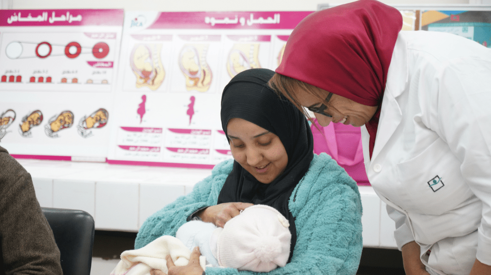 Une femme allaite son bébé avec l'aide d'une sage-femme